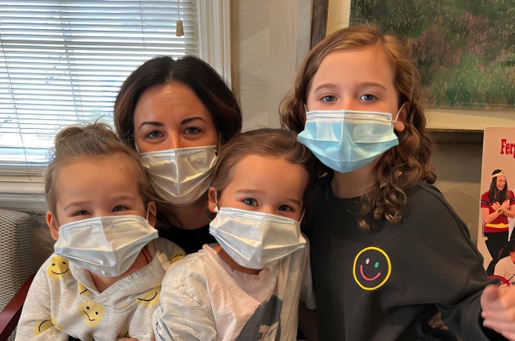 Four people wearing face masks pose together indoors at a dental office.