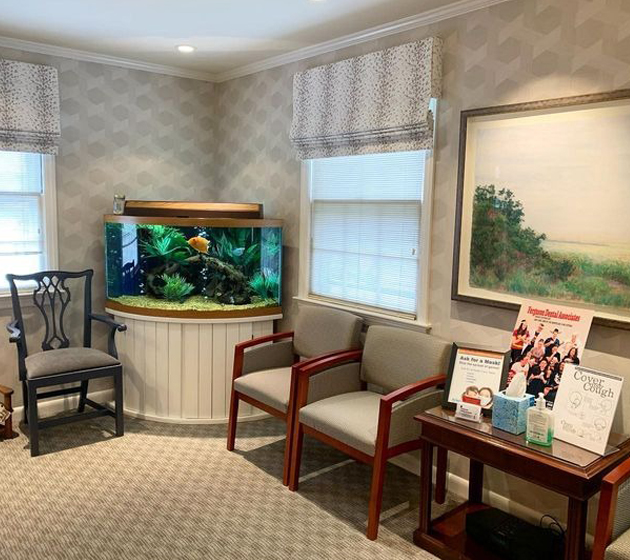 Modern dental waiting room with aquarium, comfortable seating, and professional décor.