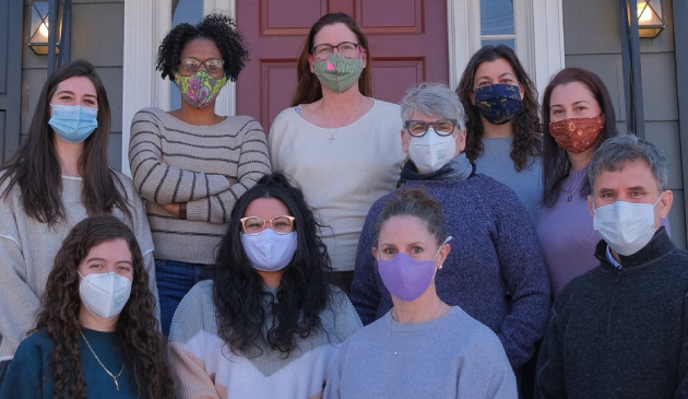 Ferguson Dental team members wearing masks posing together outside a brick building entrance.