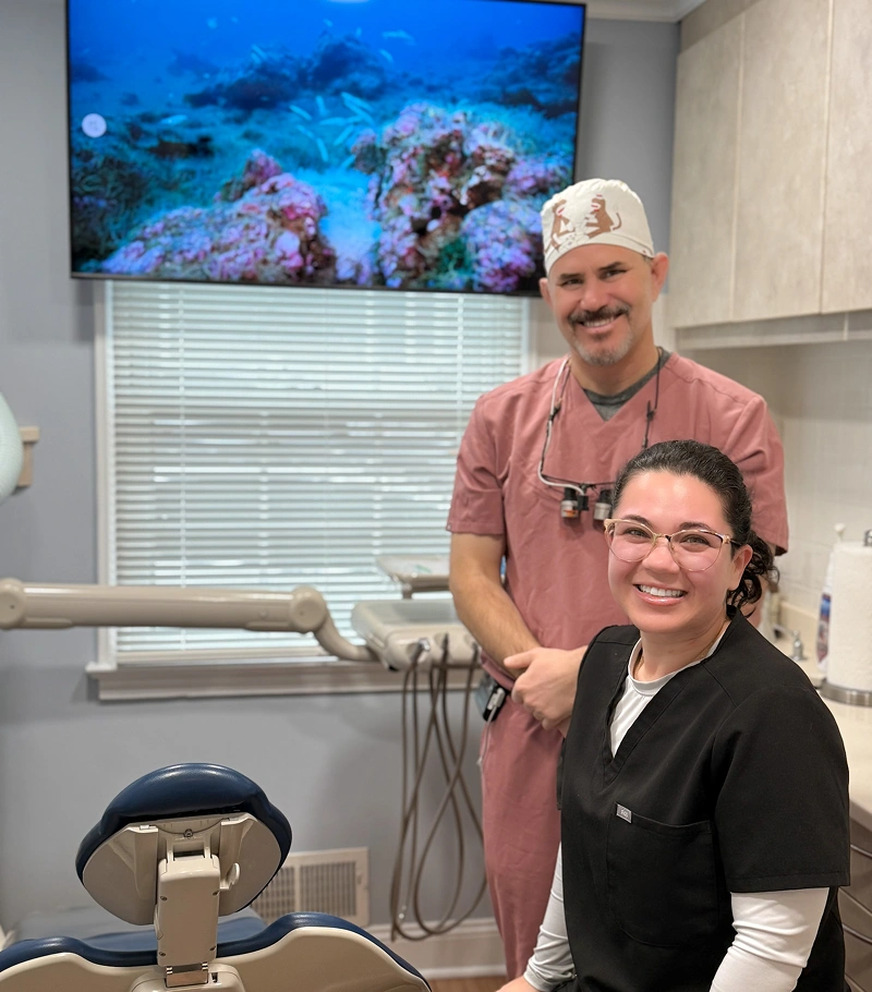 Two dental professionals posing in modern dental office with coral reef imagery on wall