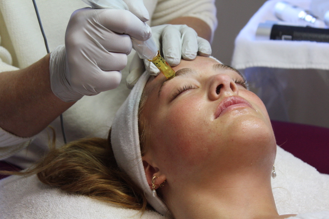 Dental professional administering injection to patient's face during cosmetic procedure in clinical setting.