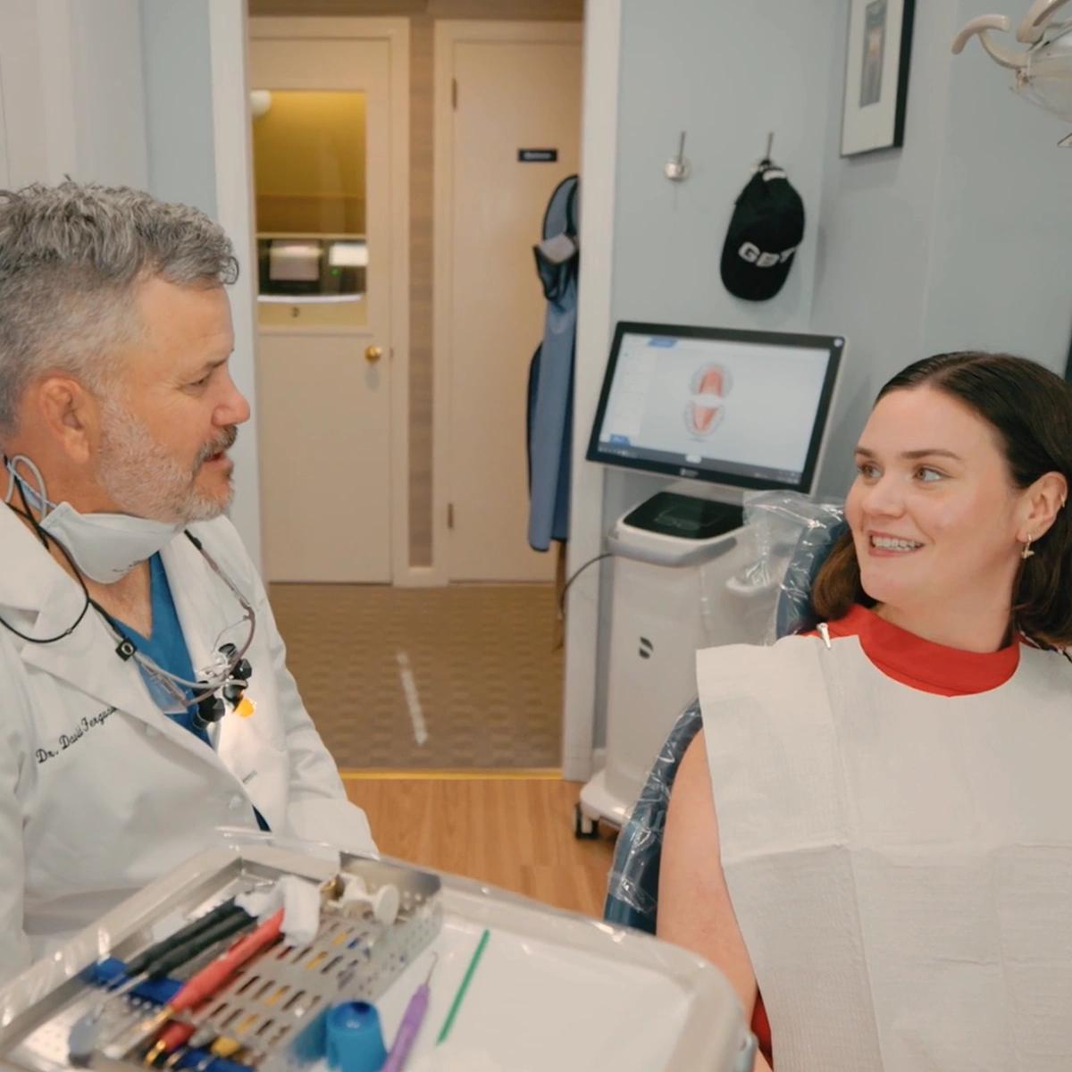 Dentist consulting with female patient in modern dental office treatment room.