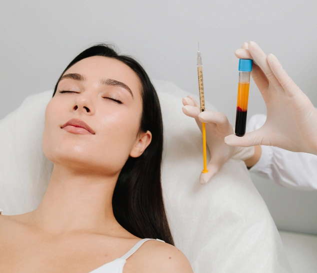 Woman receiving facial treatment with serum vials during professional skincare procedure.